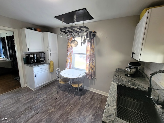 kitchen featuring stone countertops, white cabinetry, hardwood / wood-style flooring, and tasteful backsplash