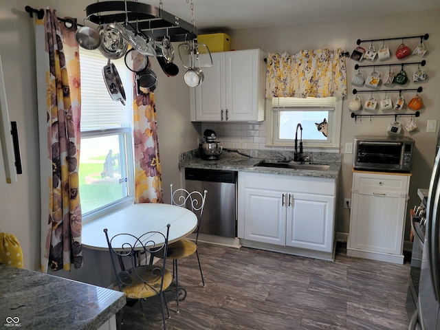 kitchen featuring stainless steel dishwasher, sink, white cabinets, and tasteful backsplash