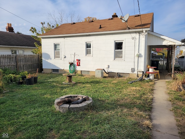 rear view of house featuring a fire pit, a lawn, and a carport