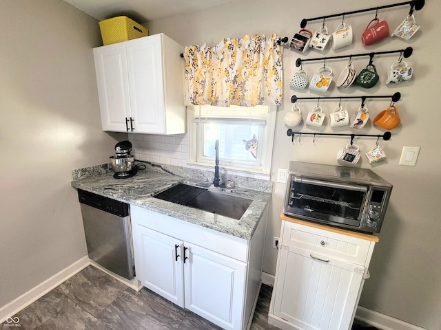 kitchen featuring decorative backsplash, dishwasher, sink, white cabinets, and light stone counters