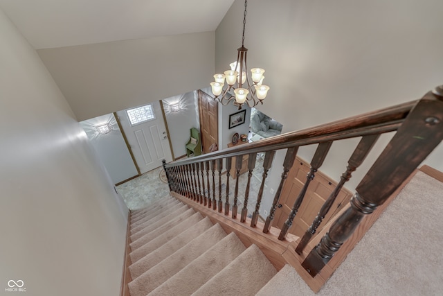 stairs with a chandelier, high vaulted ceiling, and carpet