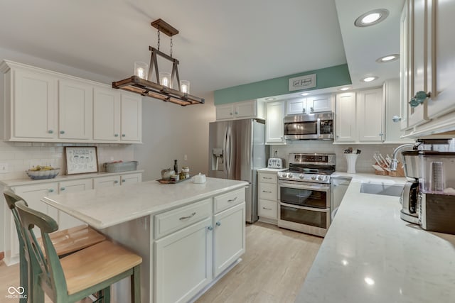 kitchen featuring sink, a breakfast bar, pendant lighting, white cabinetry, and appliances with stainless steel finishes