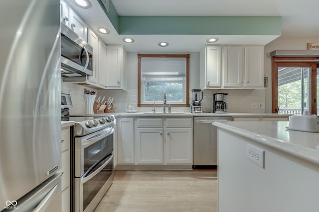 kitchen with sink, appliances with stainless steel finishes, decorative backsplash, and white cabinetry