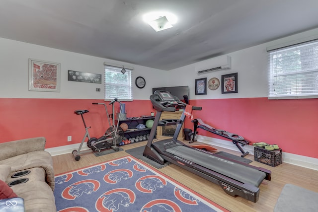 exercise area with a wealth of natural light, a wall mounted AC, and wood-type flooring