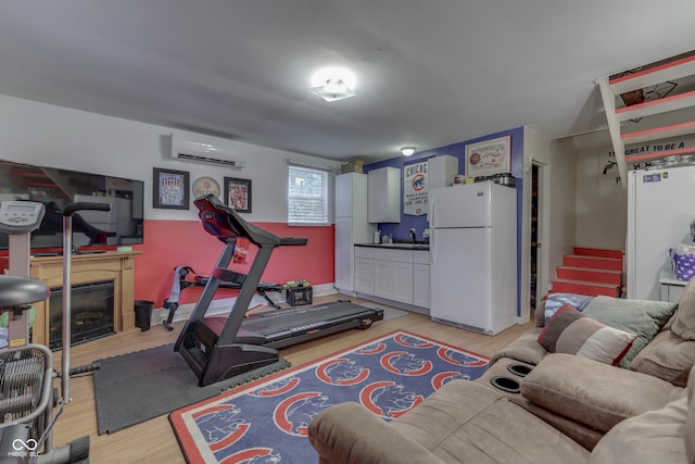 exercise area featuring an AC wall unit, sink, and light wood-type flooring