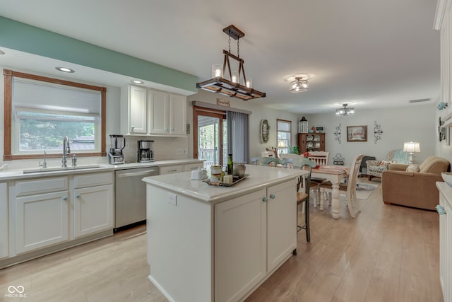 kitchen with white cabinetry, stainless steel dishwasher, sink, and a kitchen island