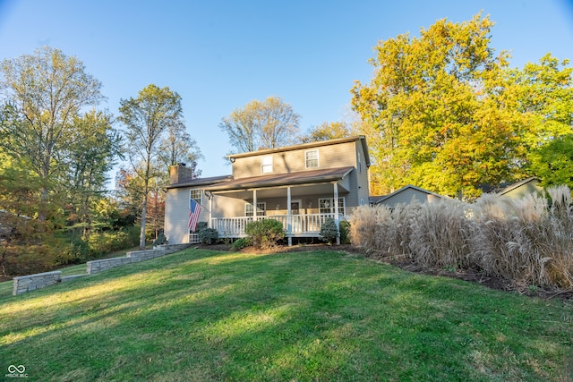 rear view of house featuring covered porch and a lawn