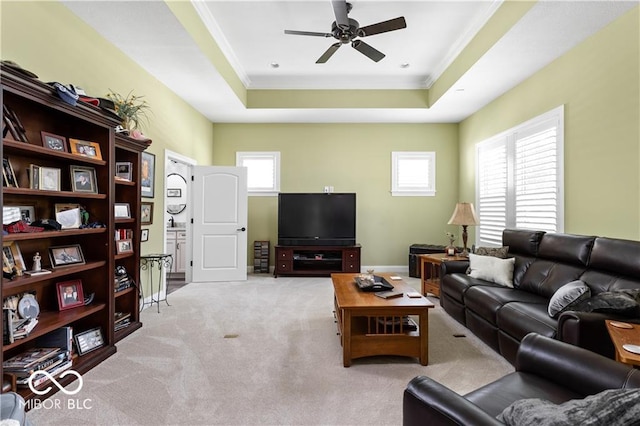 carpeted living room featuring ornamental molding, a tray ceiling, and ceiling fan