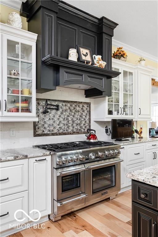 kitchen featuring range with two ovens, crown molding, white cabinetry, and light wood-type flooring