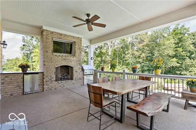 view of patio featuring grilling area, an outdoor brick fireplace, and ceiling fan