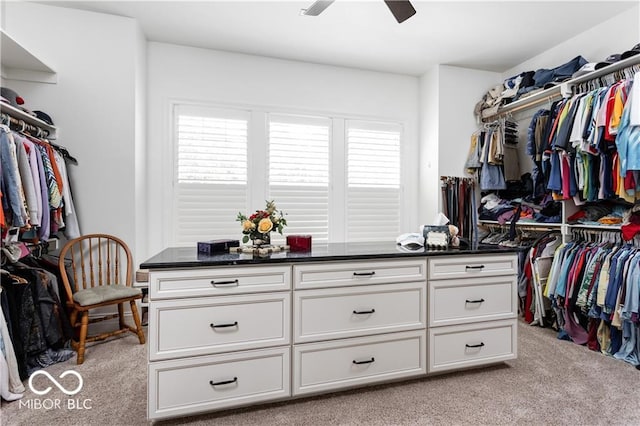 walk in closet with light carpet and ceiling fan