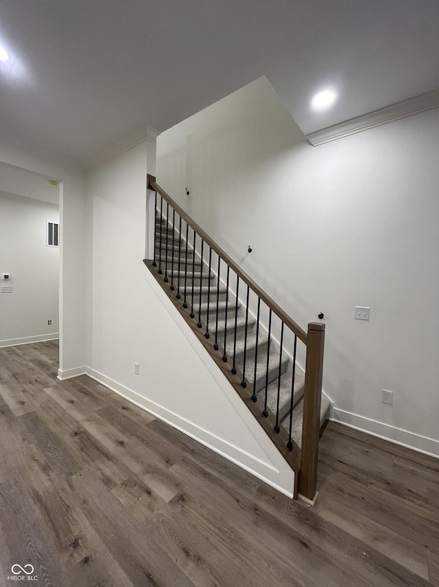 staircase with hardwood / wood-style flooring and ornamental molding