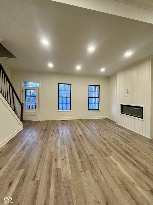 unfurnished living room featuring light hardwood / wood-style flooring and a large fireplace