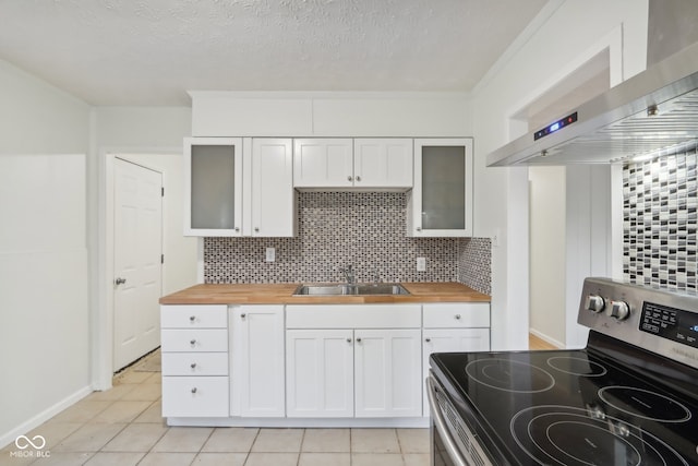 kitchen featuring stainless steel electric stove, wood counters, sink, and backsplash