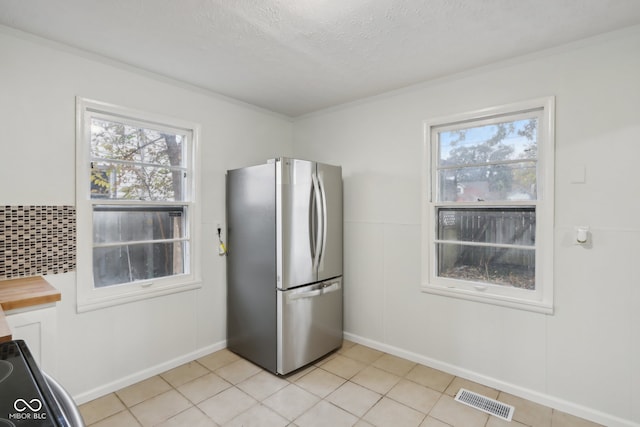 kitchen featuring ornamental molding, stainless steel fridge, butcher block counters, and a textured ceiling