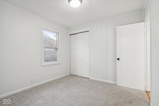 unfurnished bedroom featuring a textured ceiling, light colored carpet, and a closet