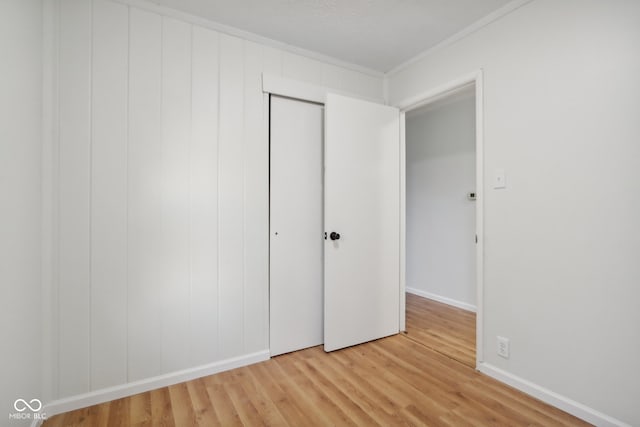 unfurnished bedroom with crown molding, hardwood / wood-style flooring, and a closet