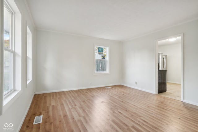 unfurnished room with ornamental molding and light wood-type flooring