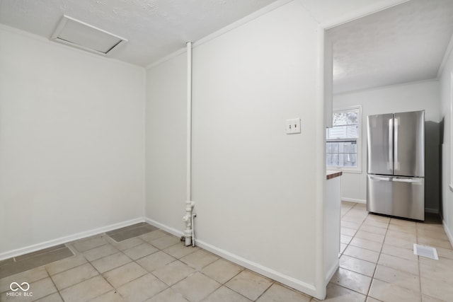 spare room featuring crown molding and light tile patterned flooring