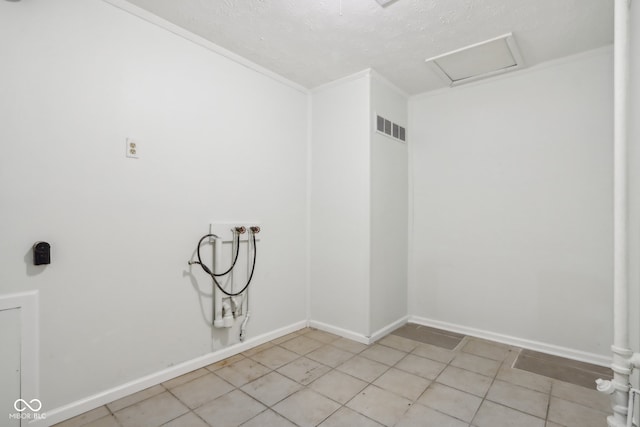 washroom featuring a textured ceiling, light tile patterned flooring, and washer hookup