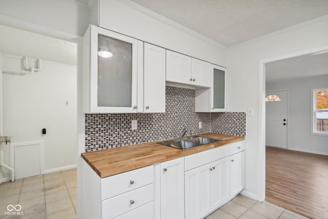 kitchen with light hardwood / wood-style floors, white cabinets, wooden counters, and tasteful backsplash