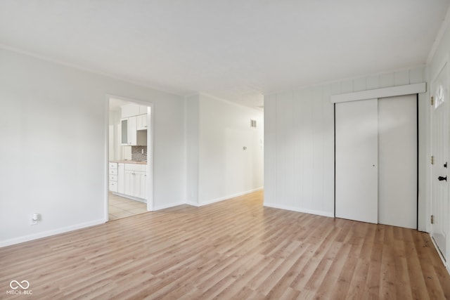 unfurnished bedroom with a closet, ensuite bathroom, and light wood-type flooring