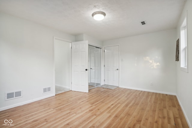 unfurnished room featuring light hardwood / wood-style floors and a textured ceiling