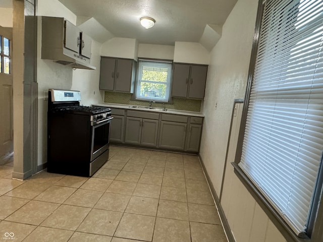 kitchen with sink, light tile patterned flooring, stainless steel gas stove, lofted ceiling, and gray cabinets