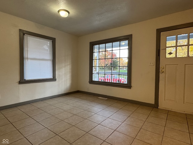 tiled foyer entrance with a textured ceiling and a wealth of natural light