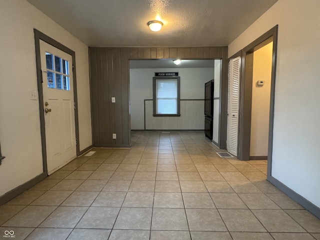 tiled foyer entrance with wood walls and a textured ceiling