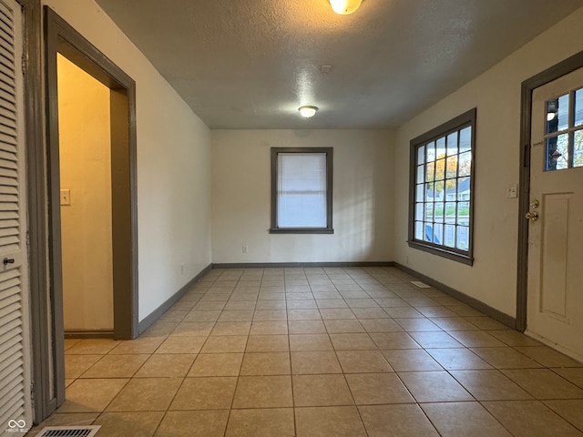 foyer with a textured ceiling and light tile patterned floors