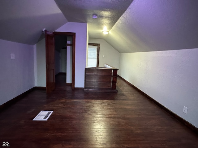 bonus room with vaulted ceiling, a textured ceiling, and dark hardwood / wood-style flooring