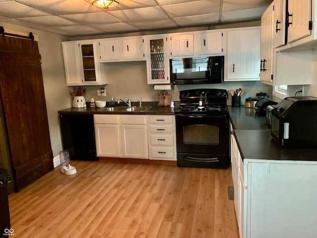 kitchen featuring sink, black appliances, white cabinetry, and light hardwood / wood-style flooring