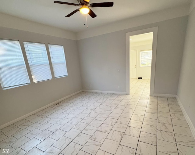 spare room with ceiling fan and a healthy amount of sunlight