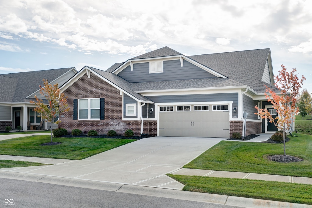 craftsman inspired home with a garage and a front lawn