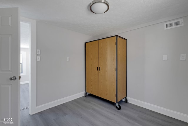 unfurnished bedroom with a closet, a textured ceiling, and light wood-type flooring