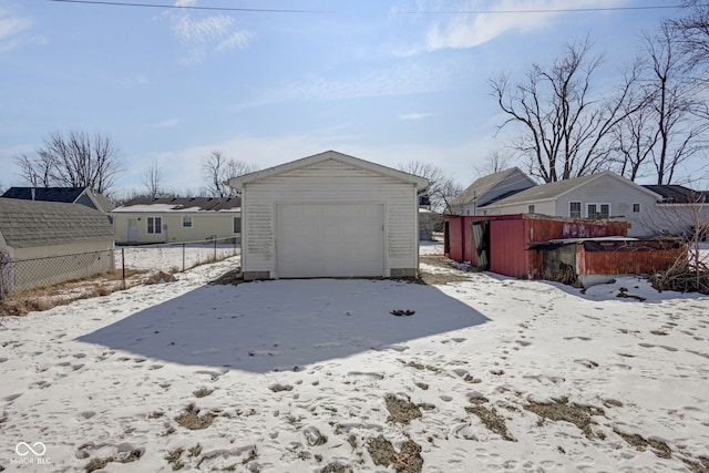 snow covered house featuring a garage and an outdoor structure