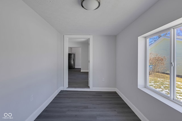 spare room featuring dark wood-type flooring and a textured ceiling