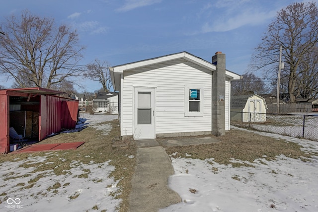 snow covered rear of property with a storage shed