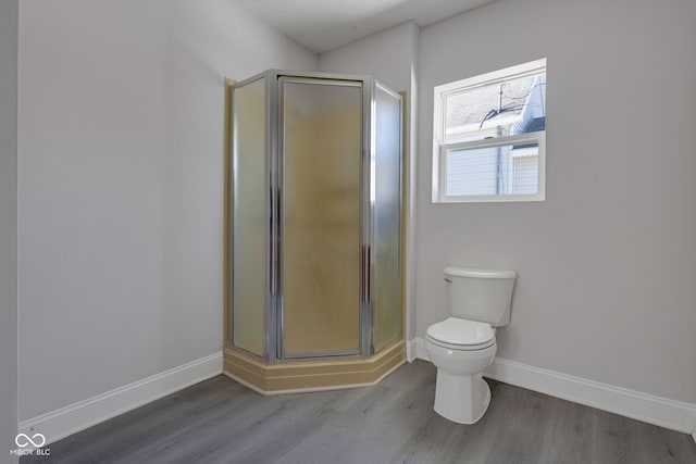 bathroom with wood-type flooring, toilet, and a shower with door