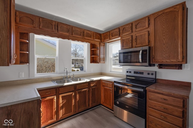 kitchen with appliances with stainless steel finishes, sink, and light hardwood / wood-style flooring