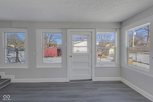 doorway to outside featuring dark wood-type flooring, a wealth of natural light, and a textured ceiling