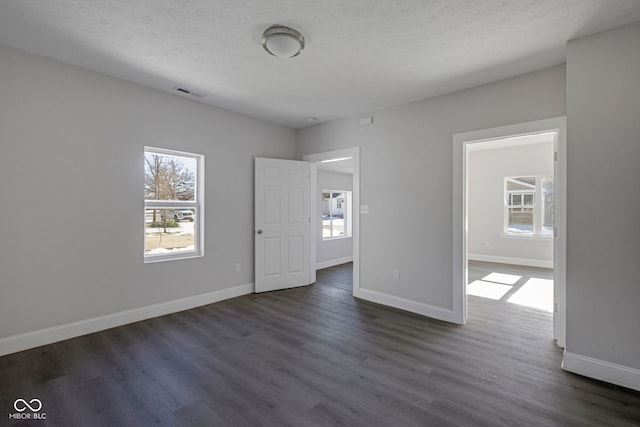 unfurnished room featuring dark wood-type flooring and a textured ceiling