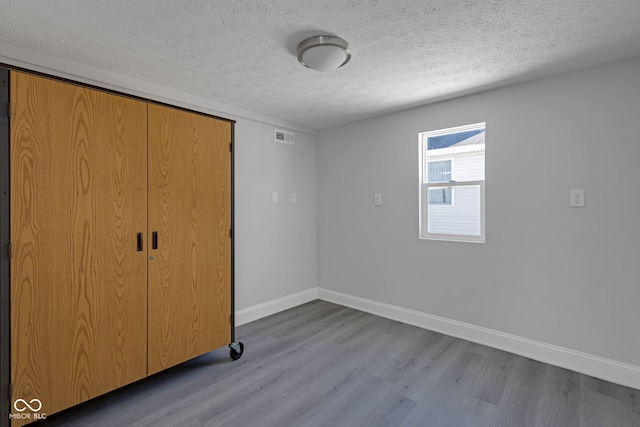 unfurnished bedroom with a closet, a textured ceiling, and light wood-type flooring