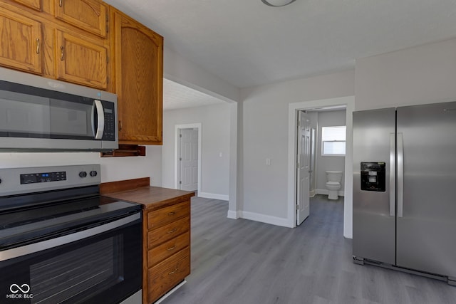 kitchen with appliances with stainless steel finishes and light hardwood / wood-style flooring