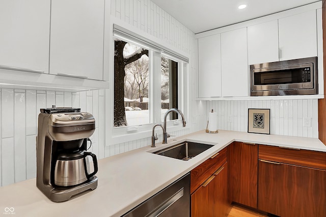 kitchen with sink, decorative backsplash, stainless steel appliances, and white cabinets