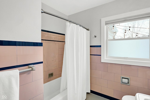 bathroom with toilet, tile walls, and shower / bath combo