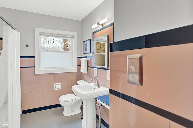 bathroom with toilet and tile walls