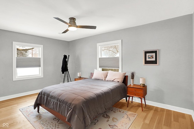 bedroom featuring ceiling fan, light hardwood / wood-style floors, and multiple windows