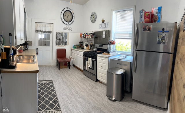 kitchen with white cabinetry, stainless steel appliances, sink, and light wood-type flooring